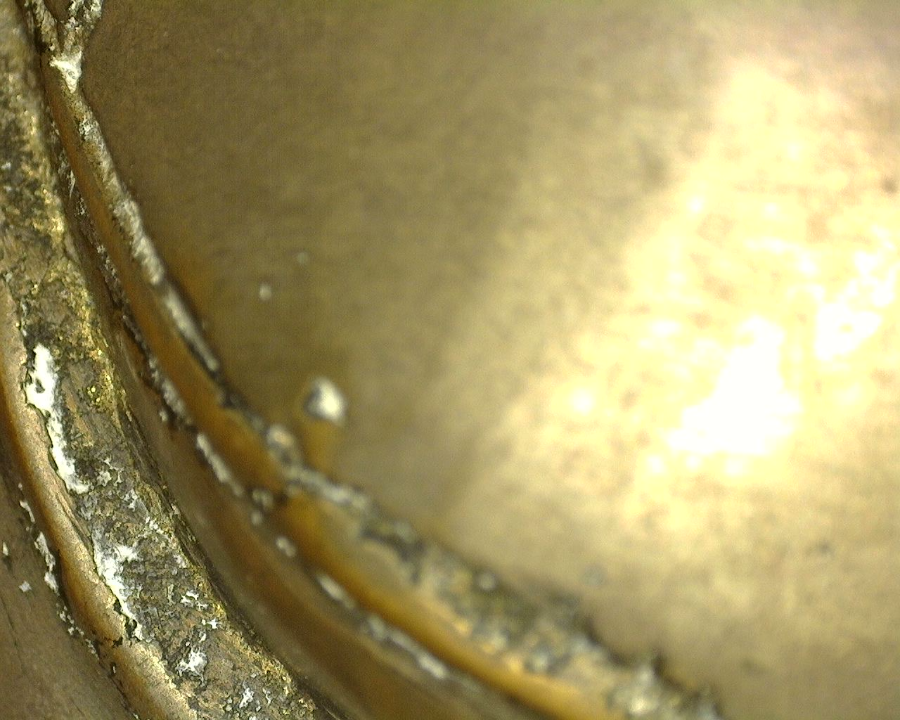 Detailopname onder strijklicht tonend de natuurlijke veroudering, minerale resten en authentieke gietnaden aan de basis van het Thaise brons.