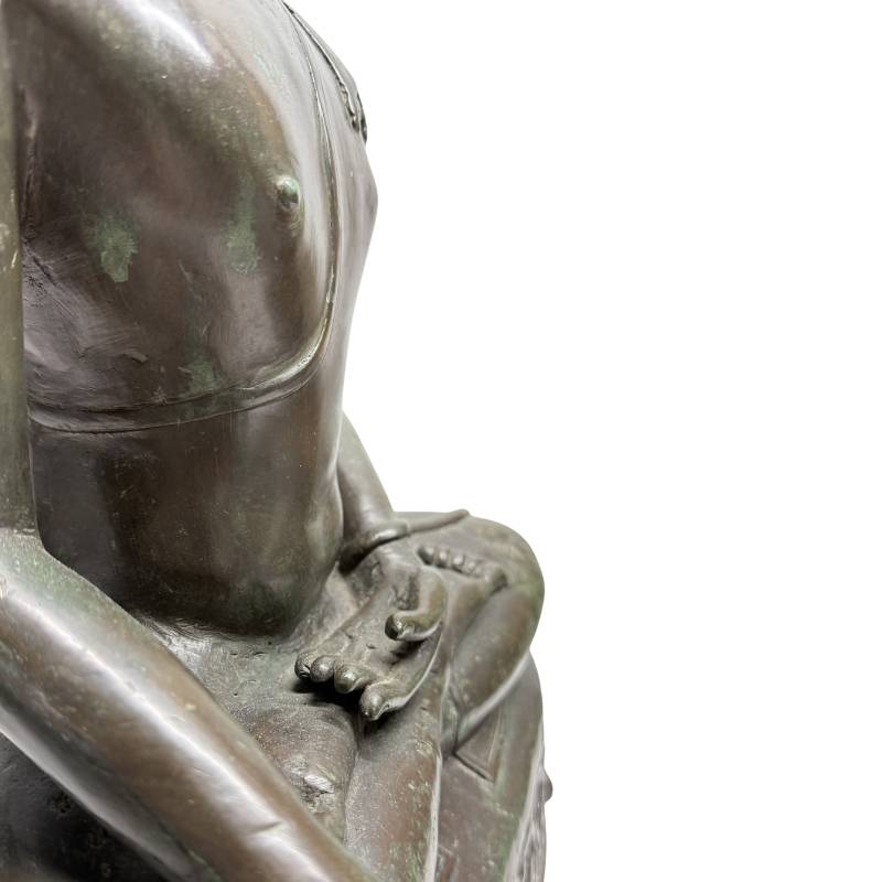 Close-up van de rechterzijde van de bronsgieting met de hand rustend over de knie in de aarde-getuige houding en de dikke wandstructuur.