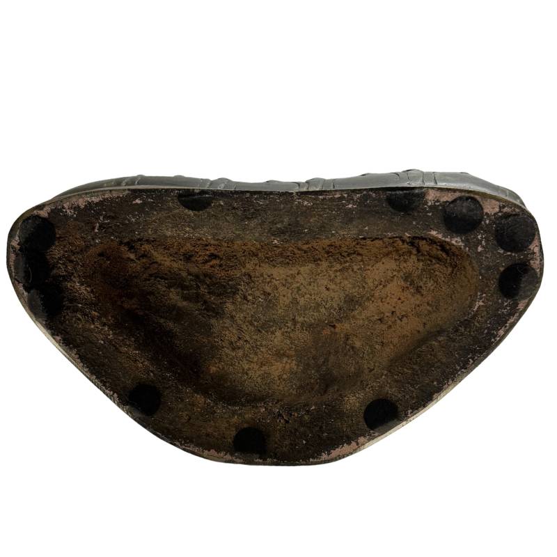 Direct onderaanzicht van de holle basis met gefossiliseerde resten van de pre-industriële gietkern en vintage vilten beschermvoetjes langs de rand.