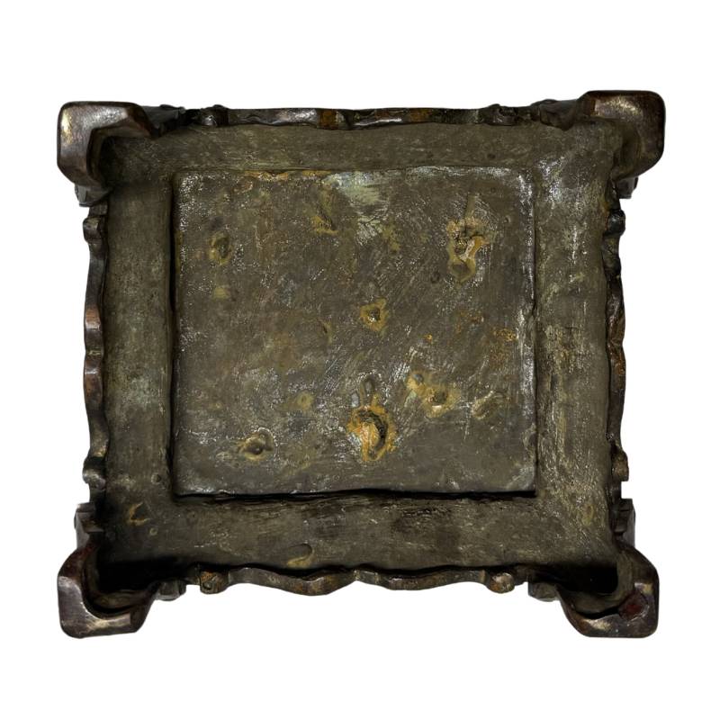 Onderzijde van de losse bronzen presentatiesokkel, tonend de originele gietsporen van de verloren was methode en de diep ingebakken malachiet oxidatie.