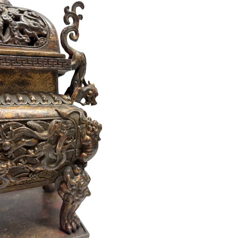 Detailopname van de rechterzijde met de gegoten leeuwenkop op de poot en de gelaagde, donkere patina op de bronswand.
