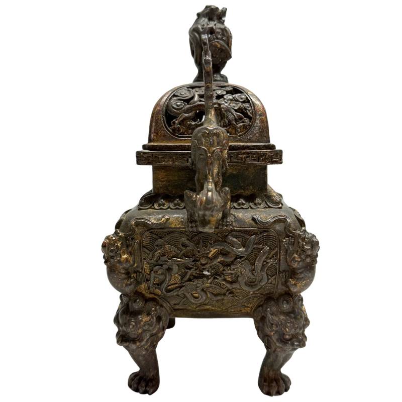 Linker zijaanzicht van de Qing-dynastie bronsgieting met de diepe, historisch doorleefde patina en vuurvergulde resten in het reliëf.