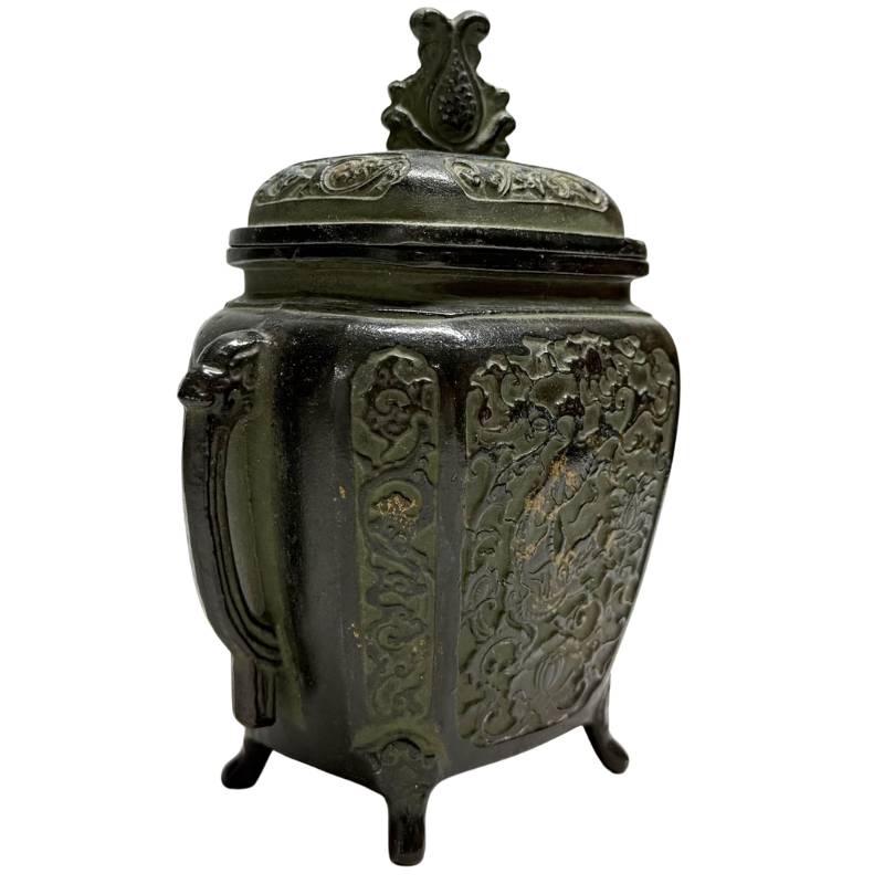Schuin vooraanzicht van de linkerzijde van het boeddhistische wierookvat, met duidelijke details van de florale motieven in het reliëf.