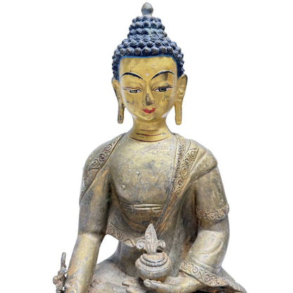 Close-up of painted eyes, red lips and gilded face of Himalayan Medicine Buddha