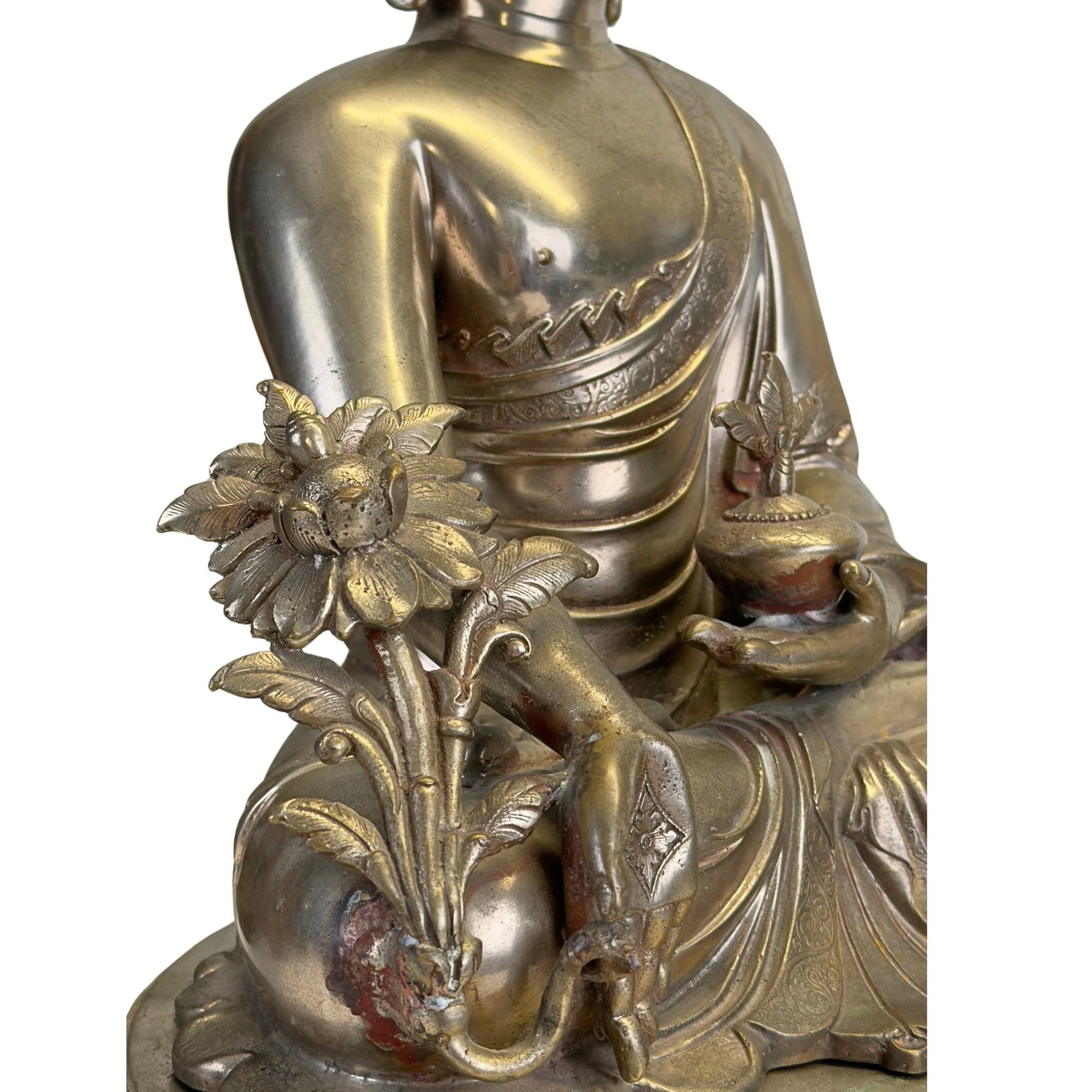 Utpala lotus and medicinal plant beside the hand of the silvered Medicine Buddha