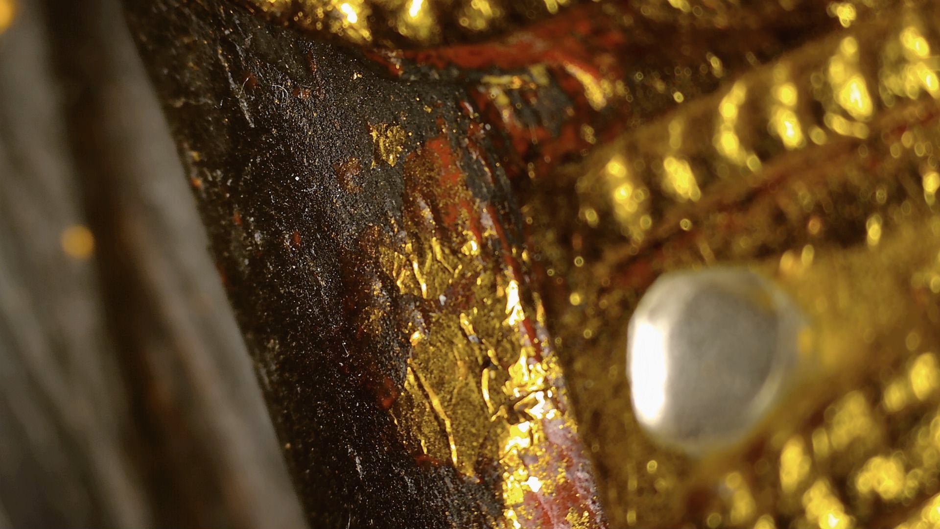 Microscopic detail of black lacquer, red ground and gilding remnants on the Burmese Buddha