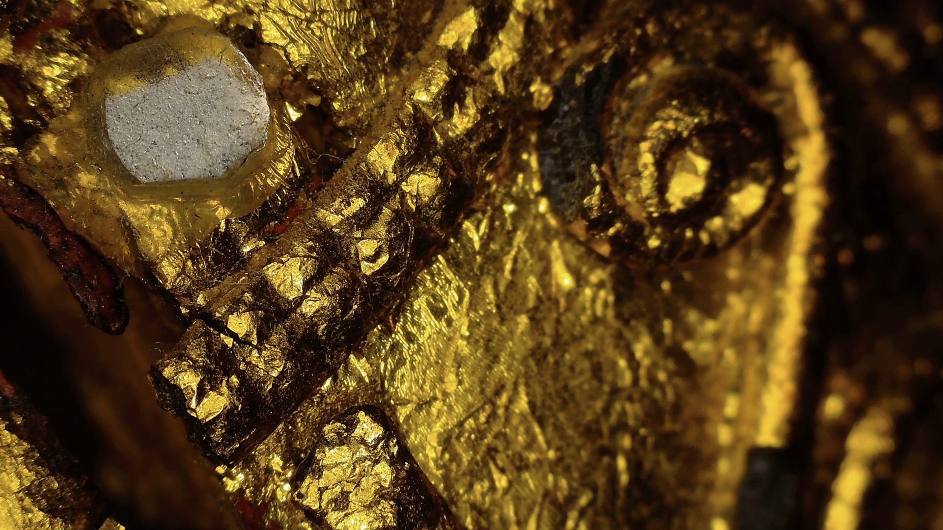 Microscopic detail of faceted glass inlay set among gilded decoration