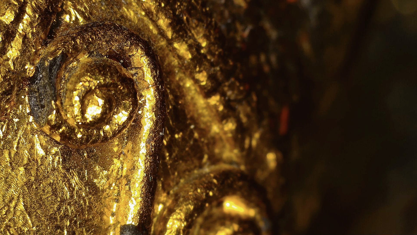 Microscopic detail of gold-leaf remnants and relief decoration on the Burmese Buddha