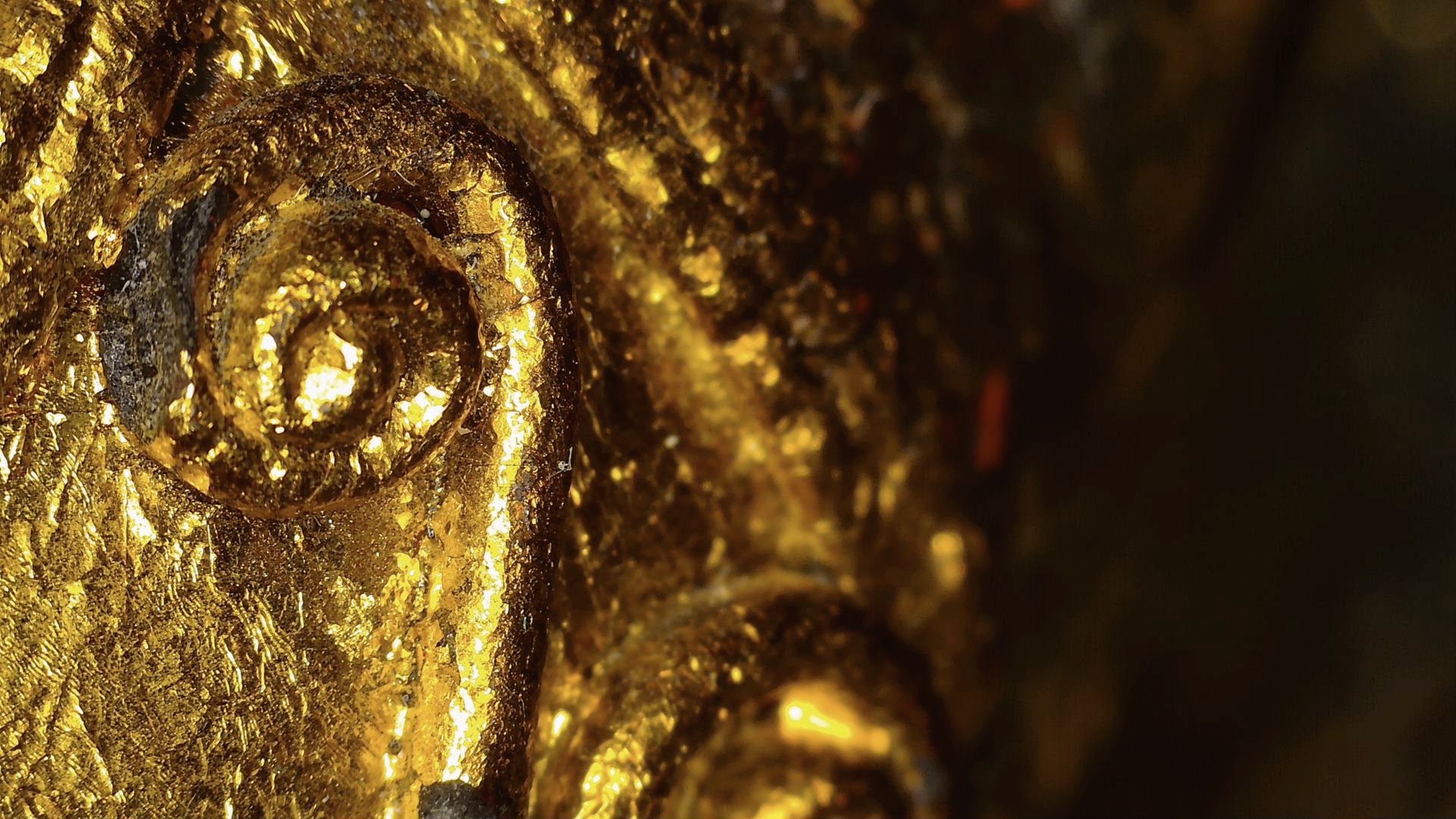 Microscopic detail of gold-leaf remnants and relief decoration on the Burmese Buddha