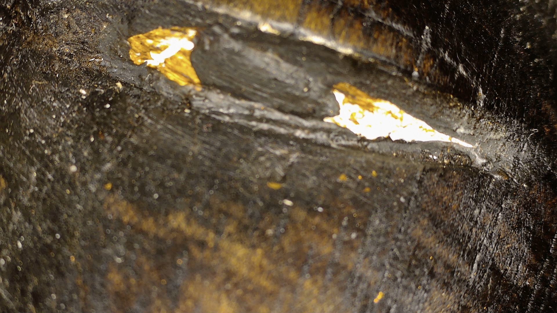 Microscopic detail of lacquered wood and local gilding remnants on the Burmese Mandalay Buddha