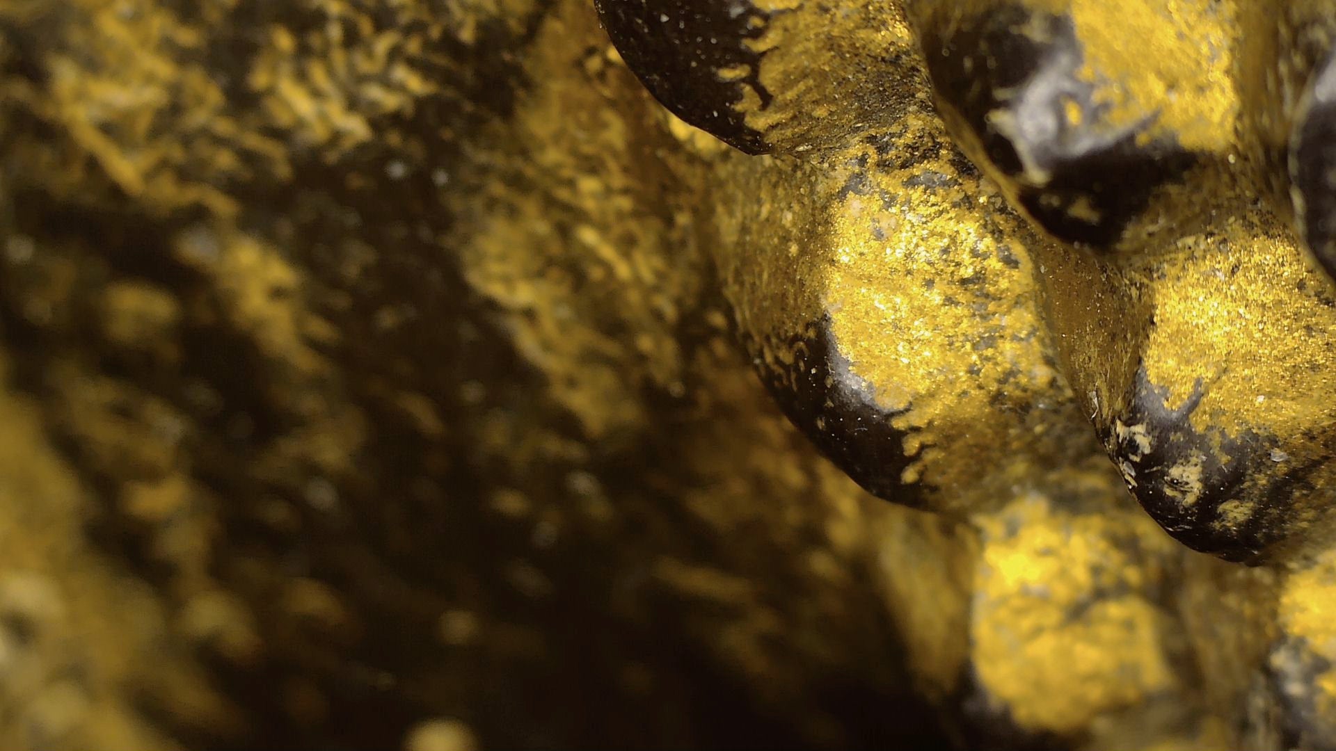 Microscopic detail of the old gold-toned surface on the face of the Burmese reclining Buddha