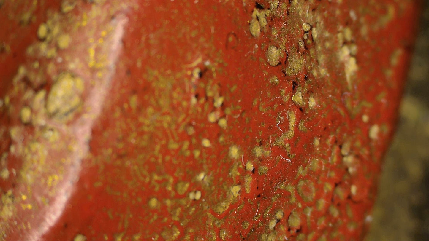 Microscopic detail of worn red polychrome on the antique Burmese reclining Buddha