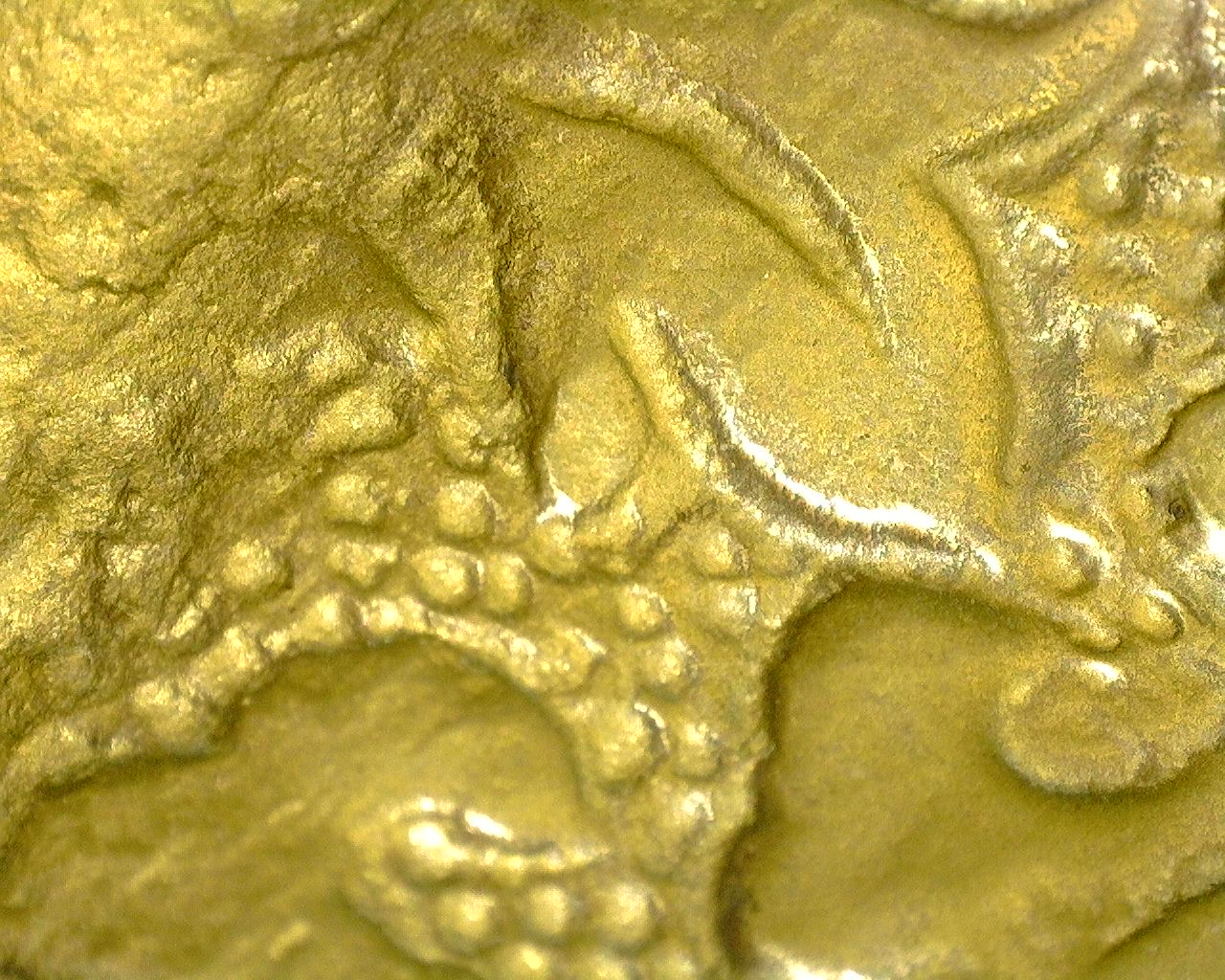Microscopische opname van fijn gegraveerde lotusdecoratie met resten van originele vuurvergulding.
