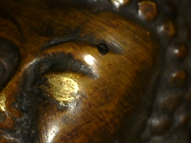 Close-up of gilding traces around the eye of Himalayan bronze Buddha