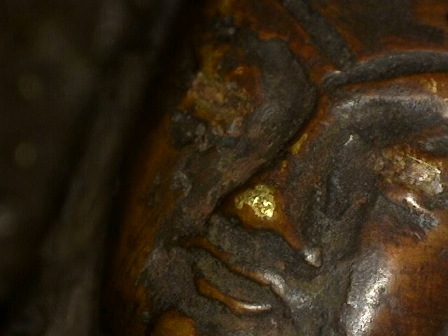 Close-up of worn face with gilding traces on Himalayan bronze Buddha
