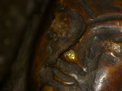 Close-up of worn face with gilding traces on Himalayan bronze Buddha