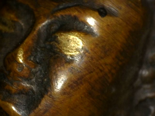 Close-up of eye, brow and gilding traces on Himalayan bronze Buddha