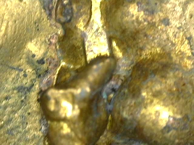 Microscopic detail of historic gilding integrated with the aged bronze surface
