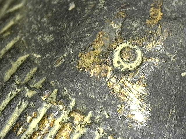 Microscopisch detail van de navel in Baphuon-stijl, tonend de scherpe gieting en de natuurlijke micro-pitting van het antieke brons.