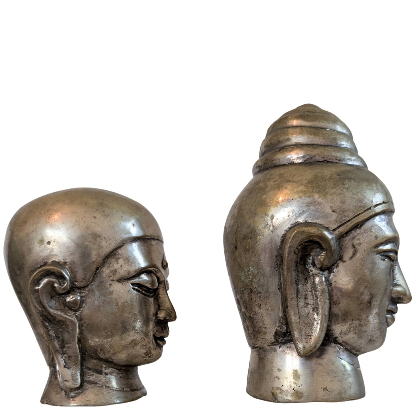 De set bronzen koppen gepresenteerd op kunstboeken in een sfeervol interieur.