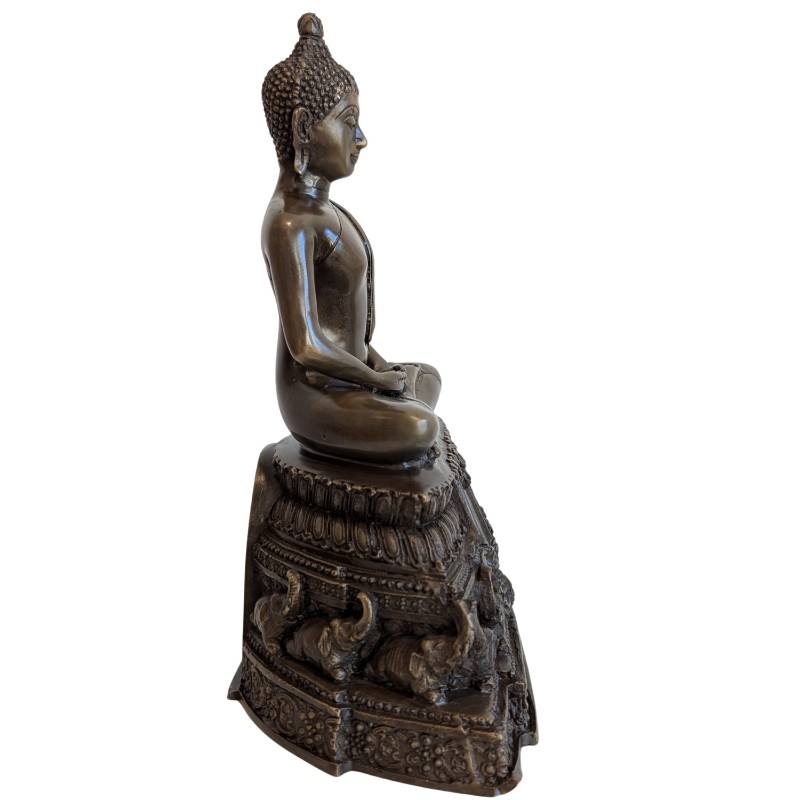 Side profile of Thai bronze meditation Buddha on tiered elephant pedestal