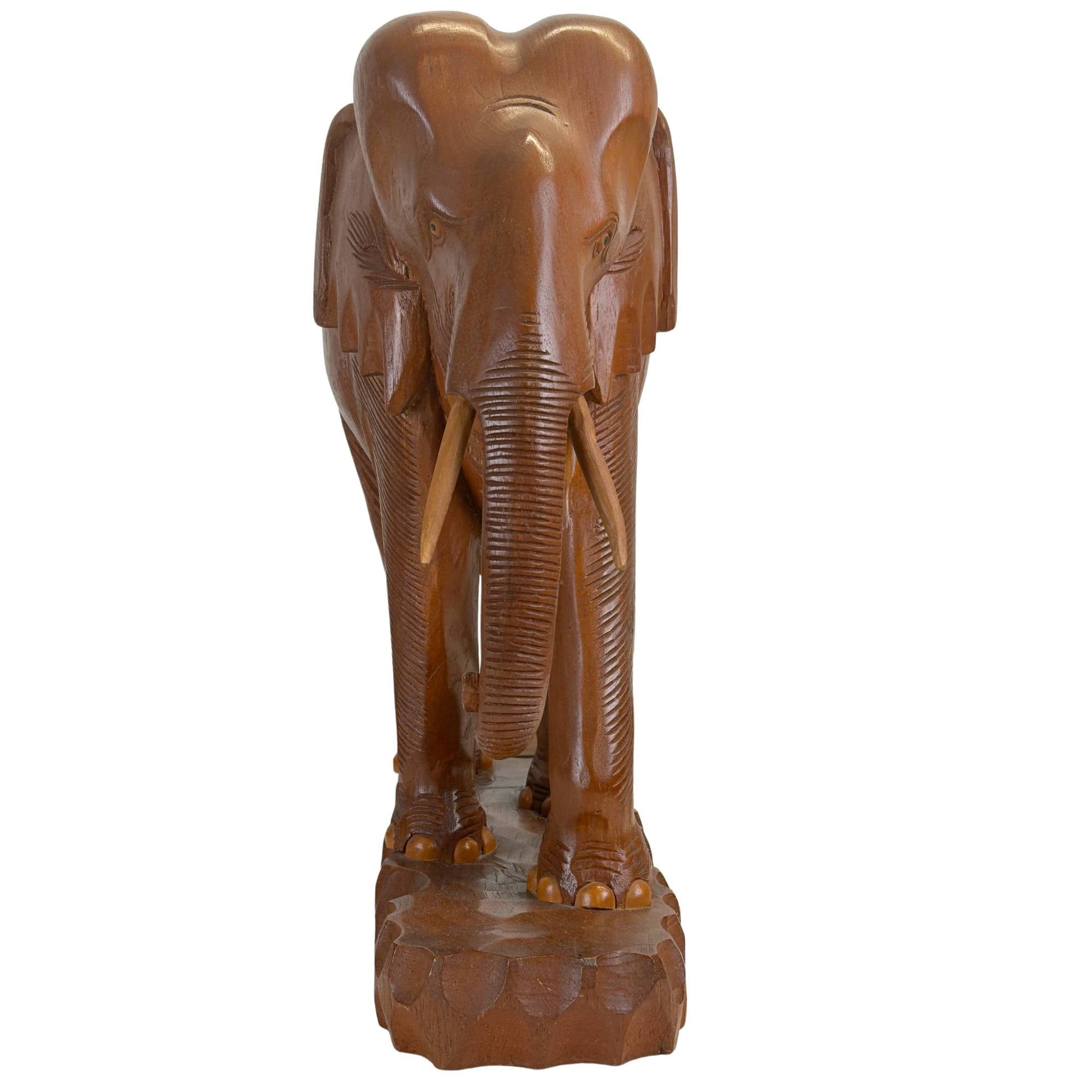 Vooraanzicht van de middelste handgesneden teakhouten olifant met neerwaartse slurf en lichte slagtanden.