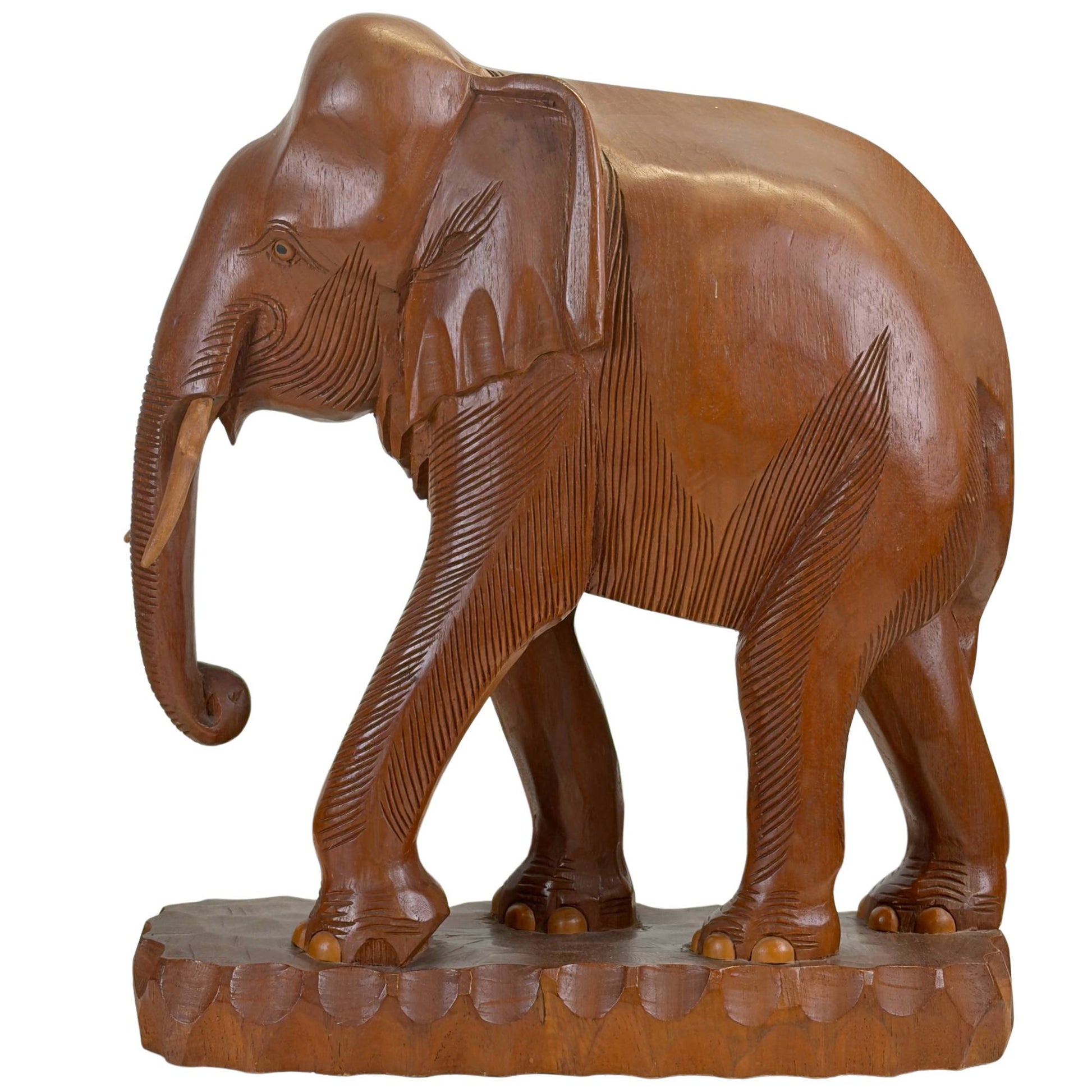 Schuin vooraanzicht van de kleinste olifant sculptuur, tonend de dynamische loophouding en de goudbruine nerf van het massieve tropische hout.