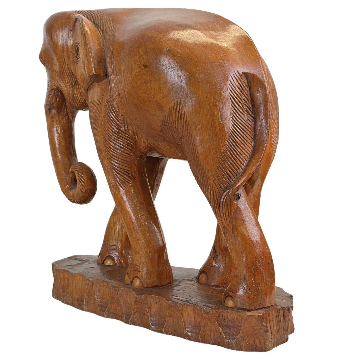 Schuin achteraanzicht van de kleinste handgesneden teakhouten olifant, tonend het volumineuze snijwerk van de rug en de compacte loophouding op de bewerkte basis.