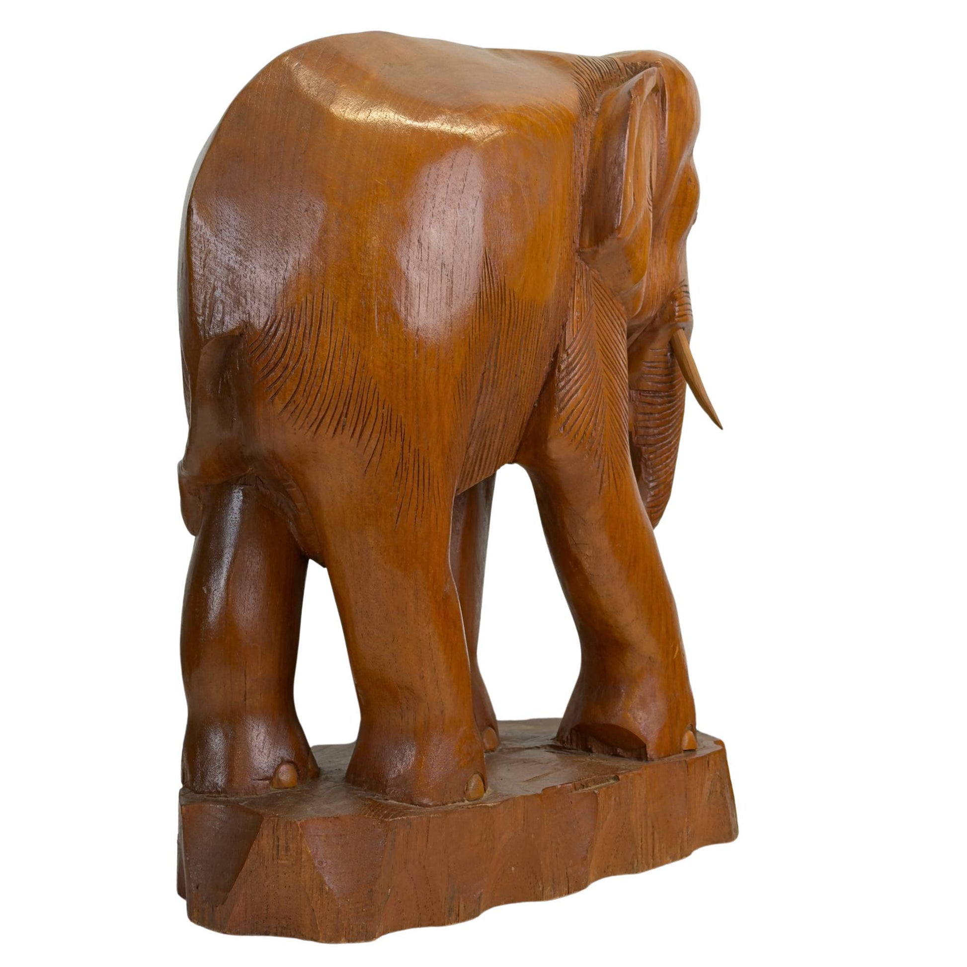 Schuin achteraanzicht van de hardhouten olifant, illustrerend de pre-industriële snijlijnen op de achterpoten en flank.