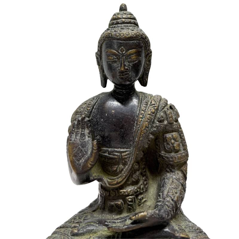 Close-up of gilded face and raised hand of Abhaya Mudra Buddha