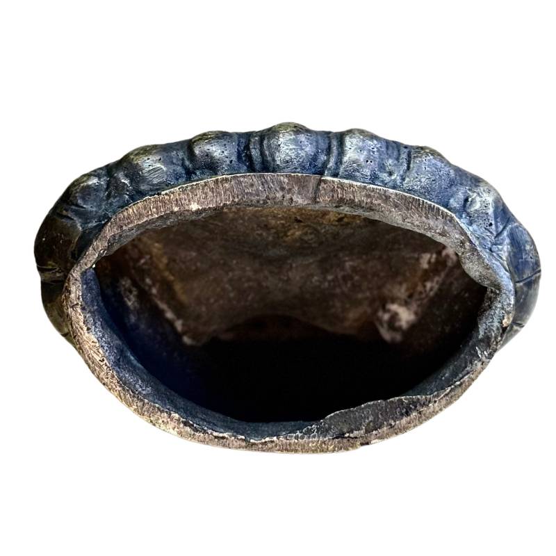 Onderzijde van antiek lama beeld tonend de massieve gietstructuur en historische patina