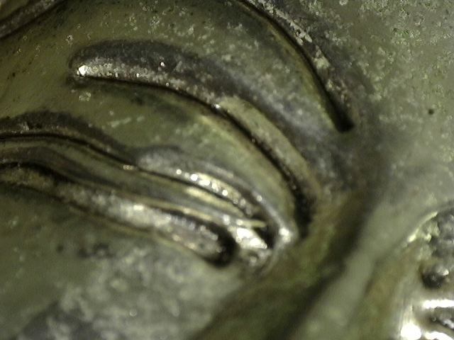 Richly engraved base of the silver-toned seated Buddha