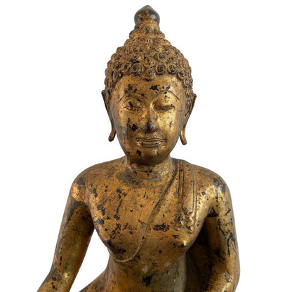Detail of the Buddha's serene face, curled hair and worn fire gilding