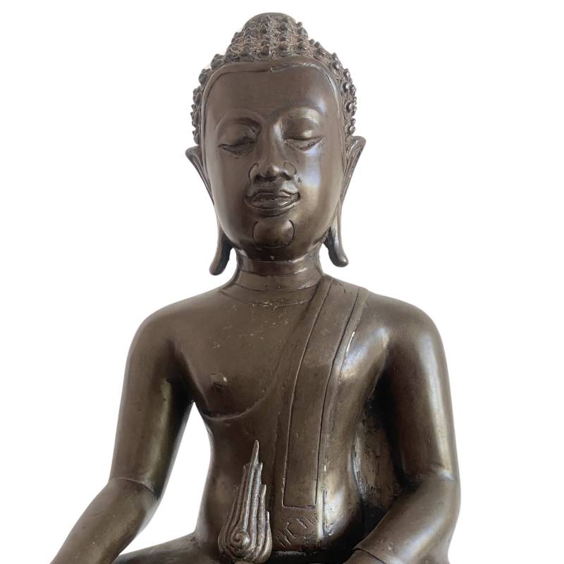 Detail of the Buddha's face without the flame finial, with the detached piece visible below