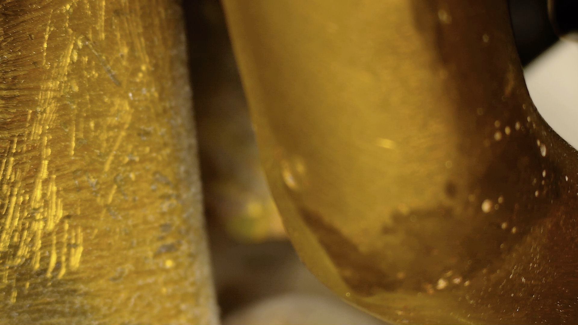 Microscopic view of old scratches and brown patina on the antique Tibetan Buddha