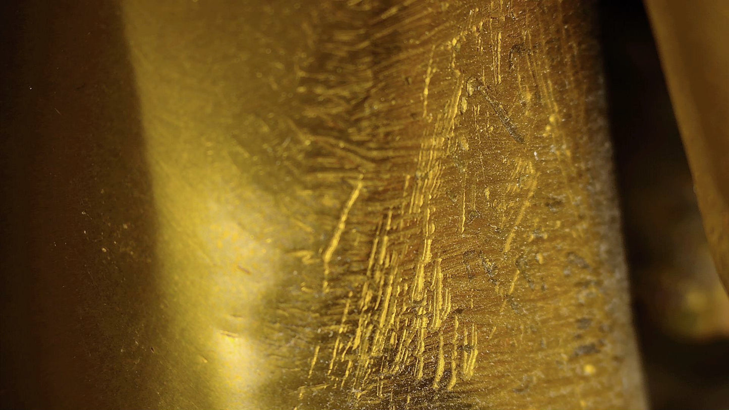 Microscopic detail of old scratches and hand-finishing marks on the Tibetan Buddha