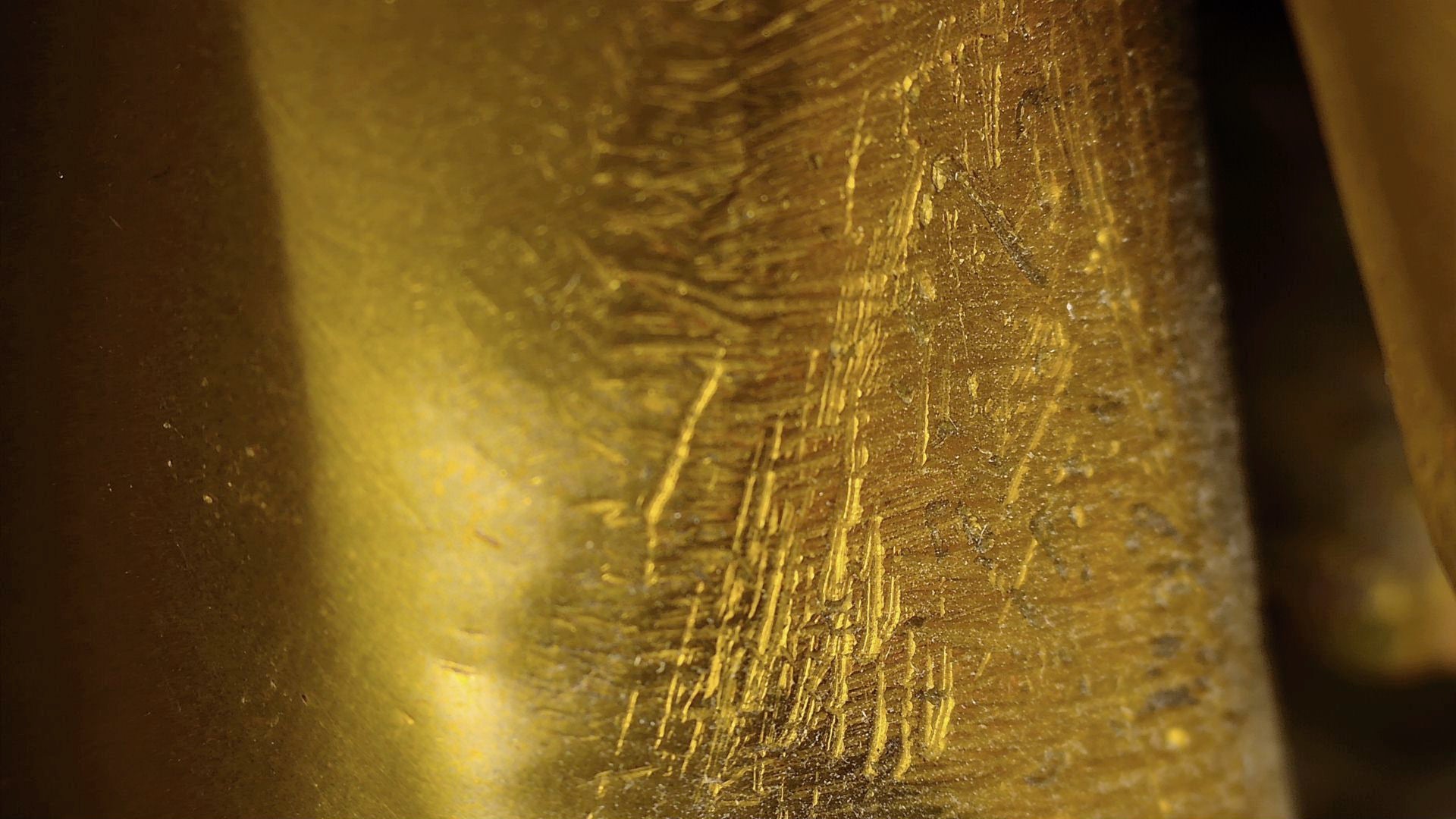 Microscopic detail of old scratches and hand-finishing marks on the Tibetan Buddha