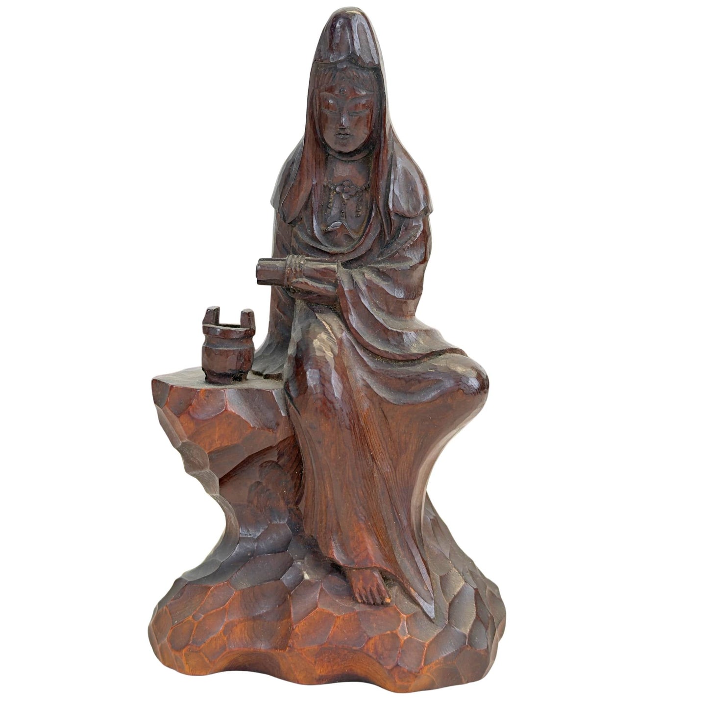 Vooraanzicht van de handgesneden Japanse houten Kannon (Guanyin) zittend op een rotsbasis met een offervat in kastanjebruine patina.